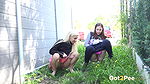 Blonde and brunette piss by the side of a building