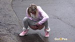 Blonde babe Claudia pisses down a drain outside