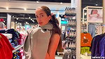 A girl walks around the store with her bare tits out