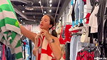 A girl walks around the store with her bare tits out