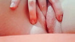 in close-up masturbating her young pussy with her fingers until it is wet
