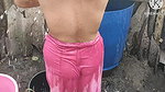 Indian house wife bathing outside with.