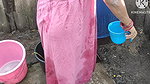 Indian house wife bathing outside with.