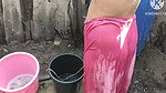 Indian house wife bathing outside with.